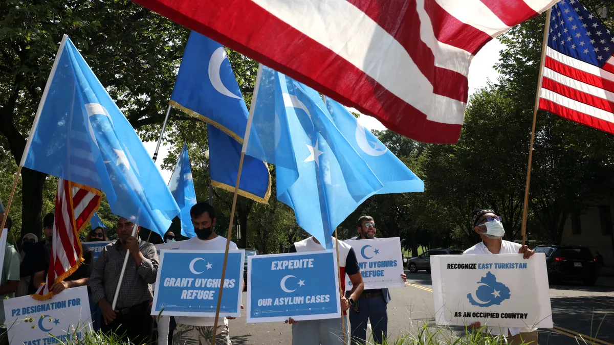 People are seen holding signs and flags.