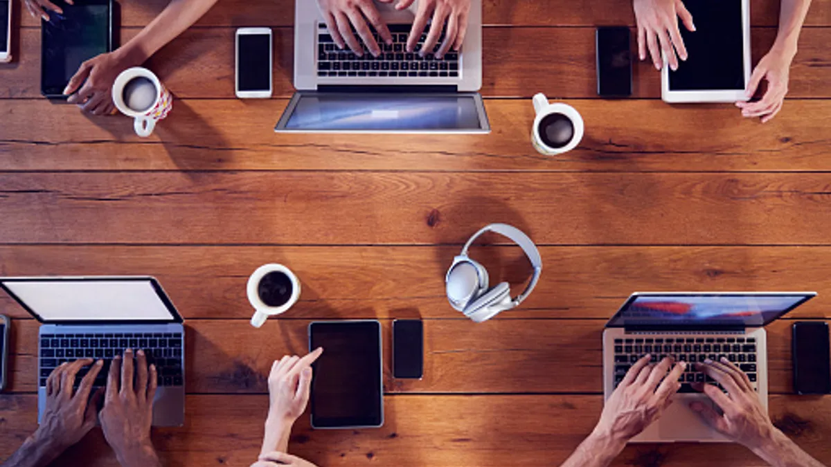 Overhead shot of young adults using technology at a table