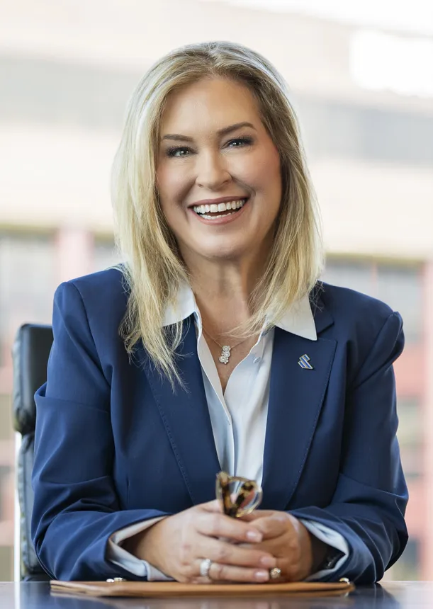 Blond woman in a blue suit smiles at the camera.