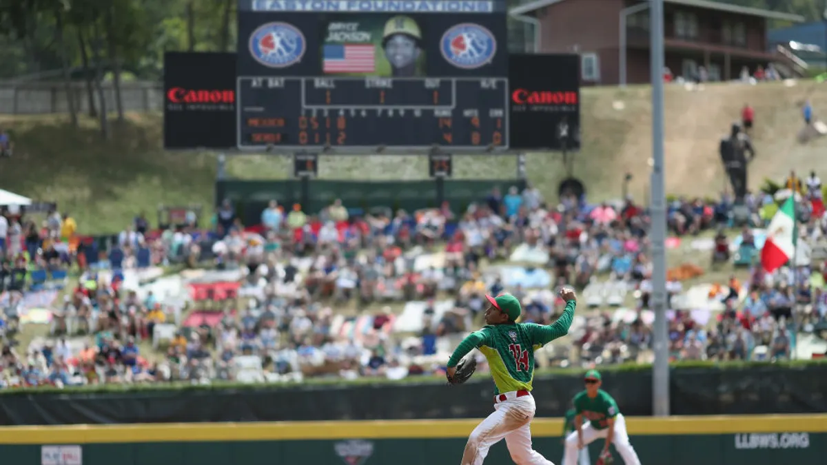 A little league baseball player throws a pitch.
