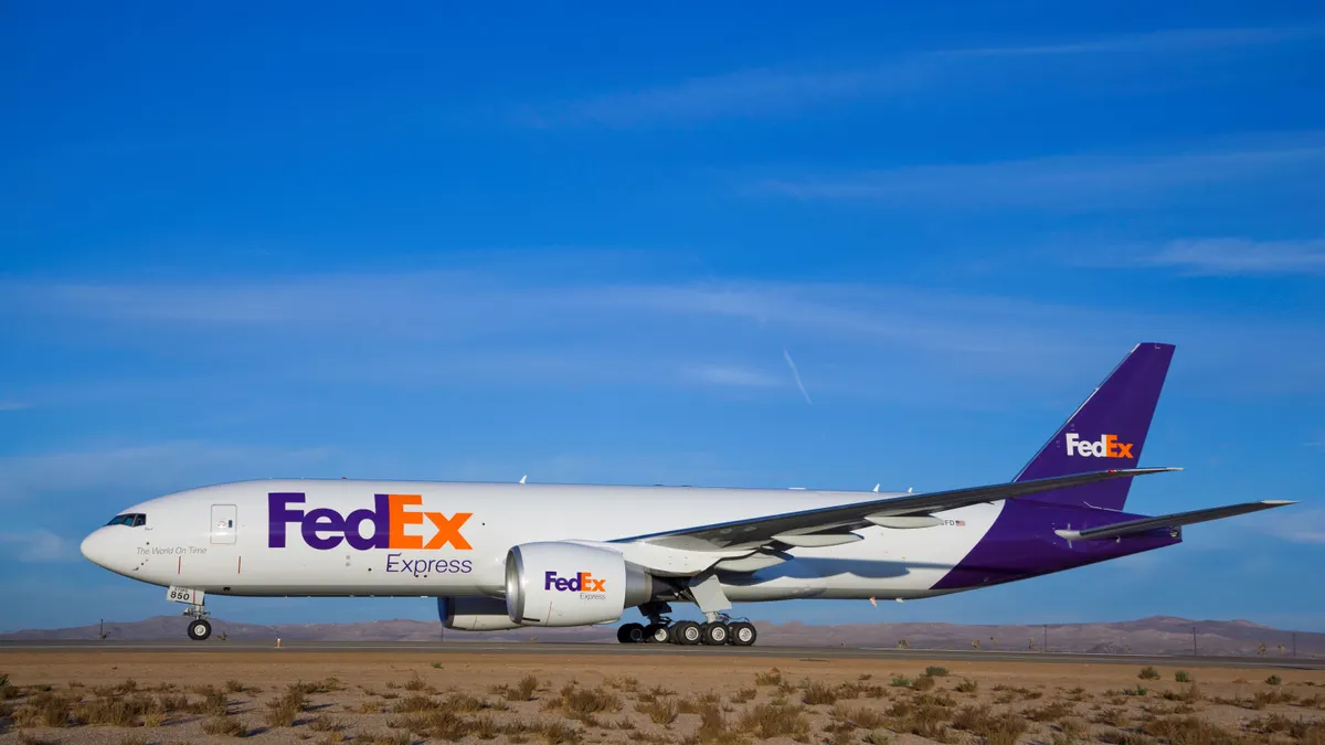 A FedEx branded airplane on a runway with a blue sky in the background.