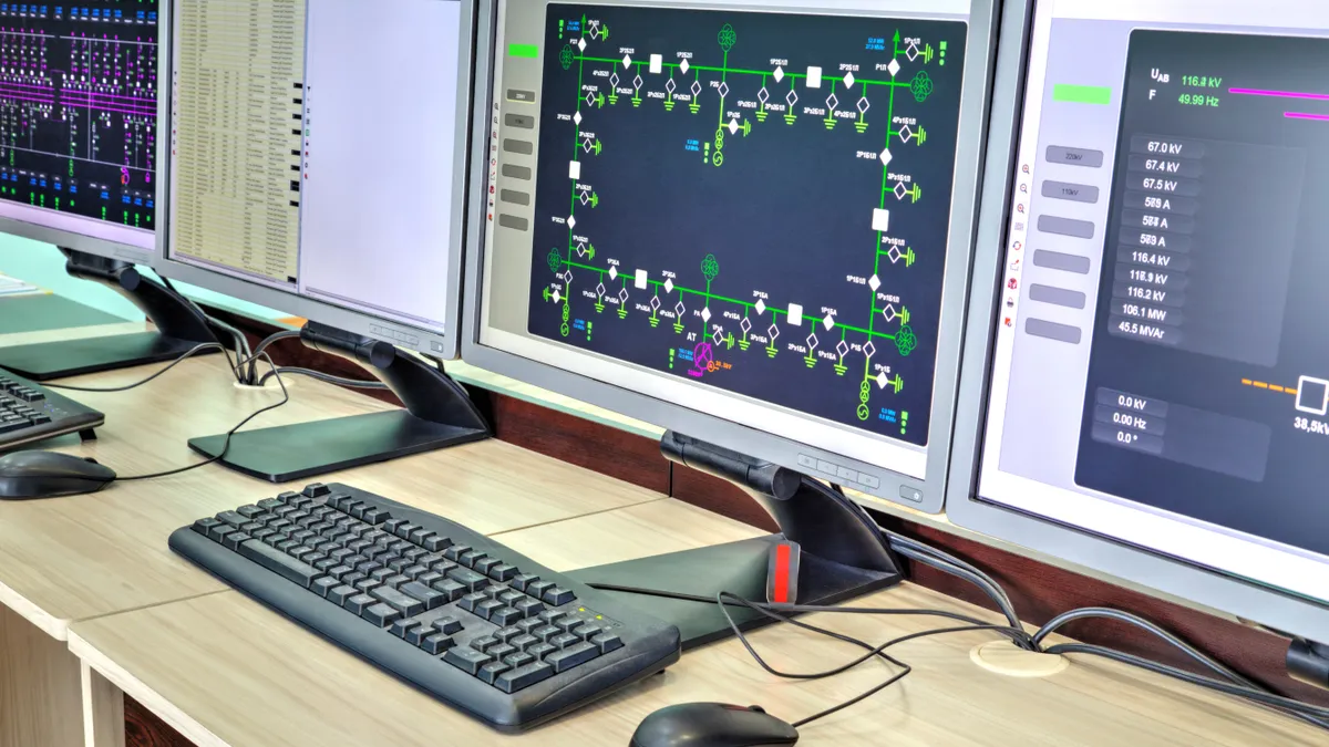 Row of computer monitors and keyboards on a table with different data and graphs on the screens