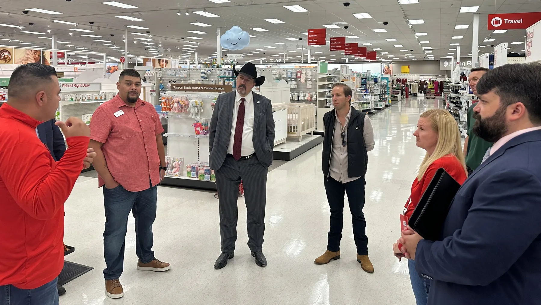 A group of people stand in a store, talking.