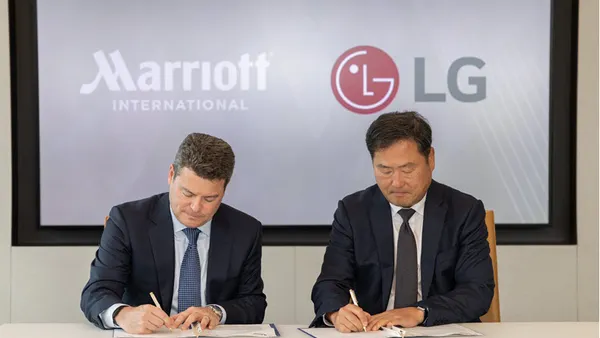 Executives from Marriott International and LG Electronics sign an agreement.