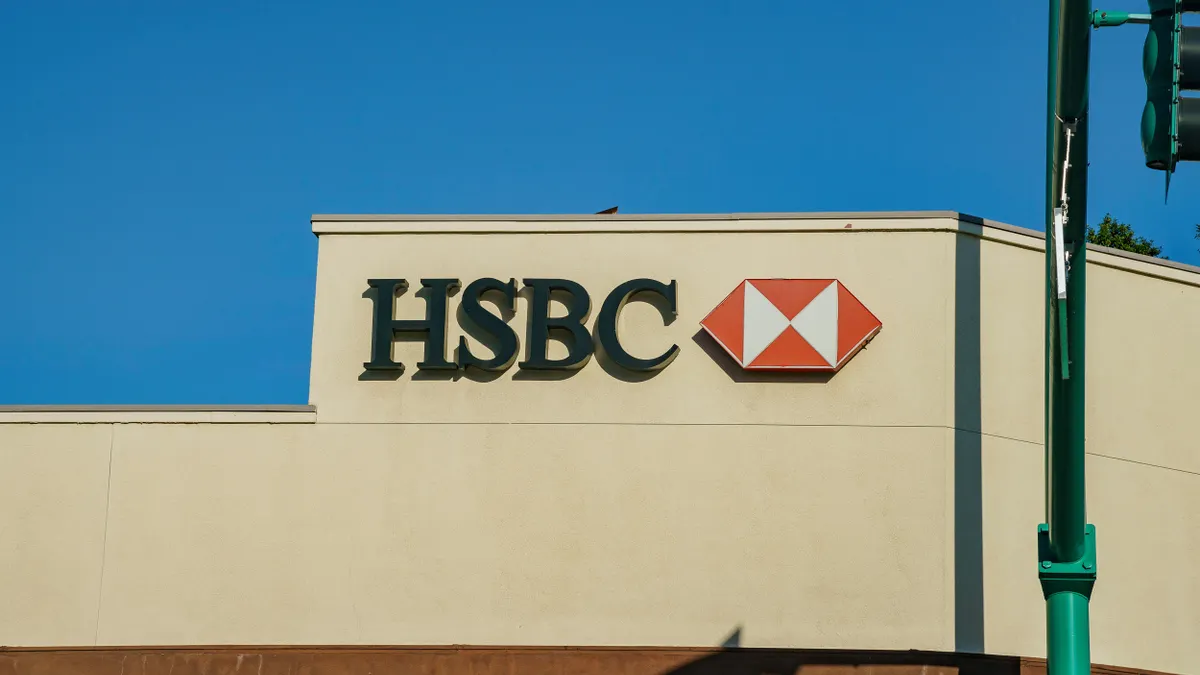 A red and white HSBC logo is prominently displayed on a warm, neutral stucco wall. 