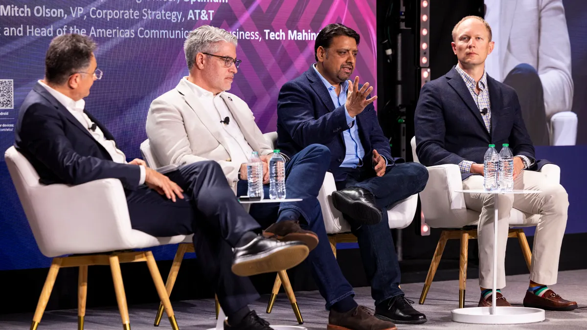 Four executives discuss the telecom industry on stage at a conference.