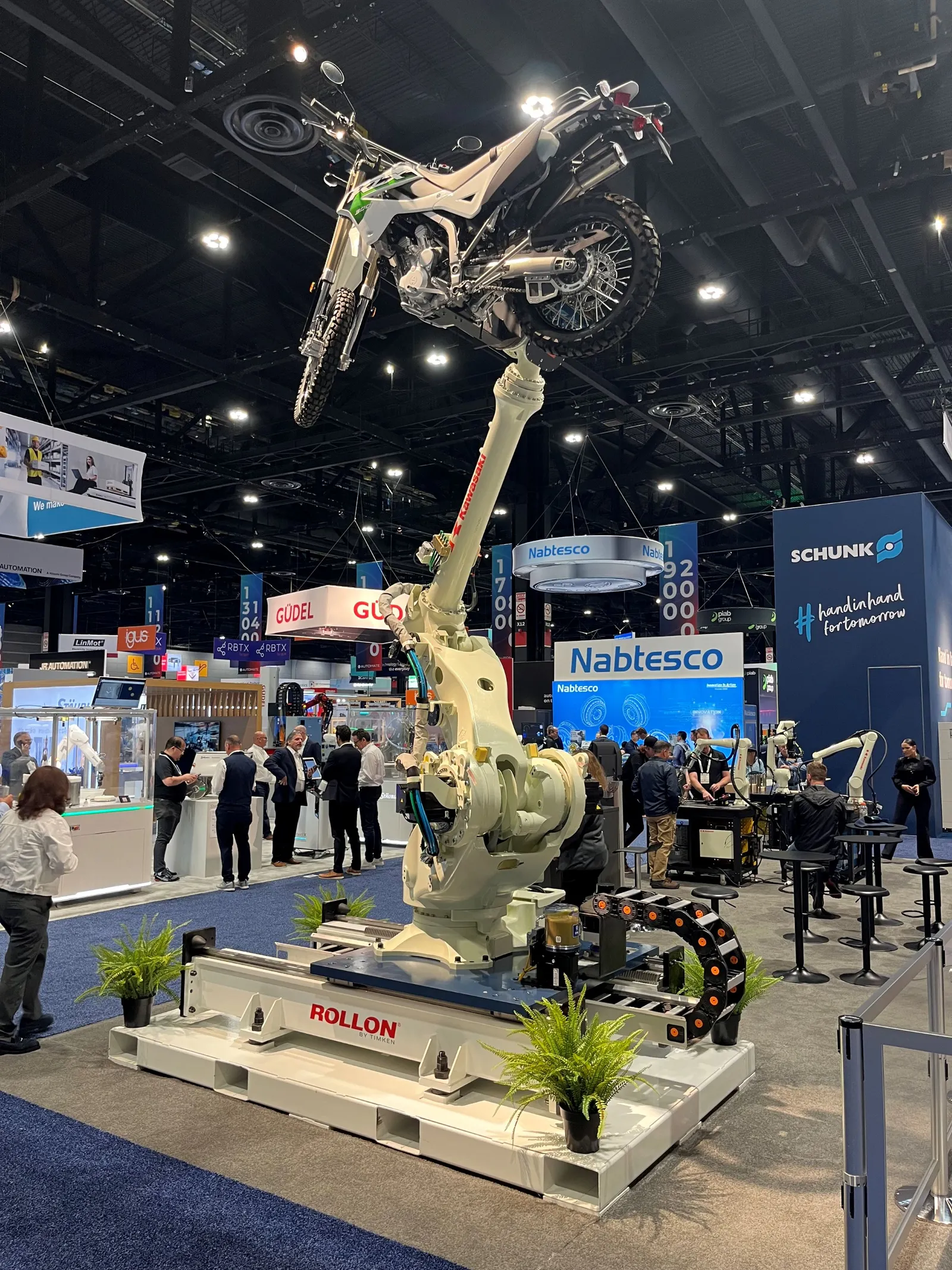 Kawasaki displays a heavy-duty industrial robotic arm carrying an off-road motorcycle at Automate 2026 in Chicago.
