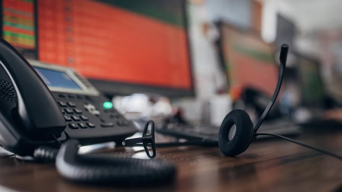 An empty desk with a headset and computer screen