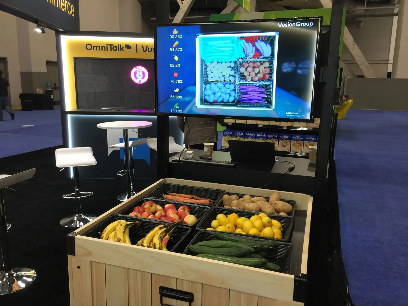 Produce on a wooden table below a video monitor