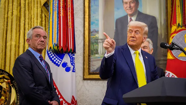 President Donald Trump stands at podium with Robert F. Kennedy Jr. on his left side