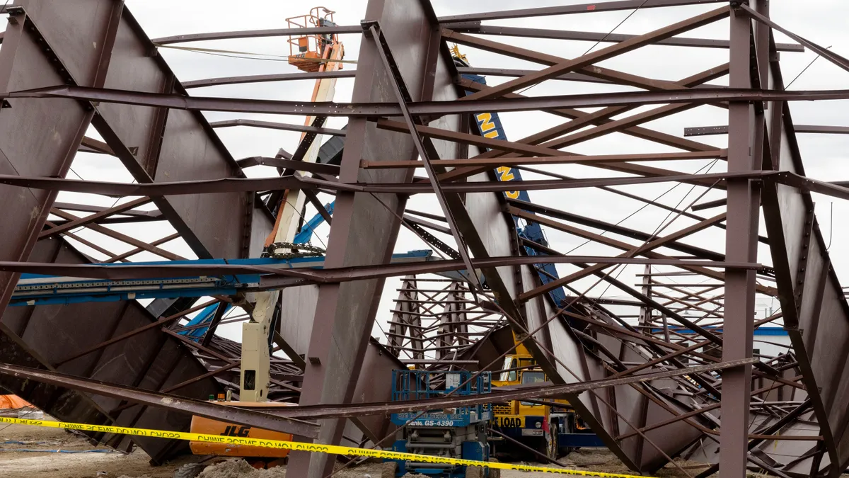 A crane is mangled under twisted and collapsed metal beams.