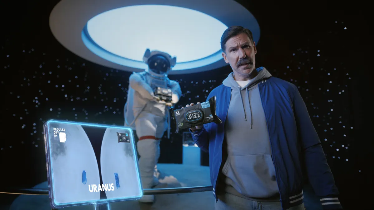 Man holds Dude Wipes in a space-themed museum exhibit