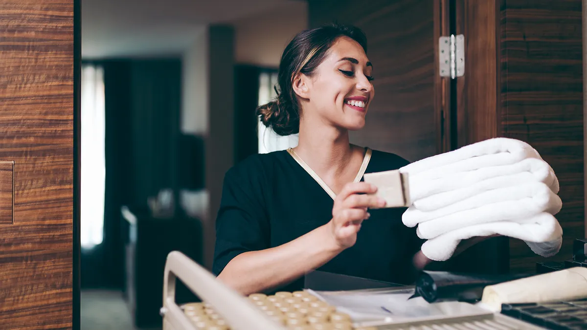 Hotel maid bringing clean towels and other supplies to hotel room.