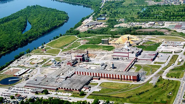 Aerial view of an industrial facility surrounded by trees and located next to waterways.