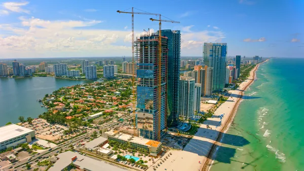 A crane hovers above a hotel tower along the beach.