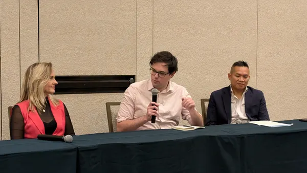 A man speaks while a woman and a man on either side of him listen to him