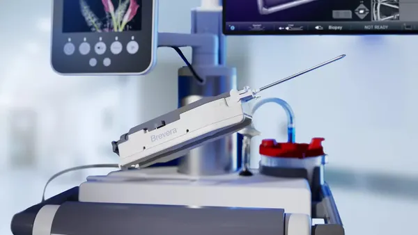 A rectangular device with a needle sitting on a cart says "Brevera" on the side.