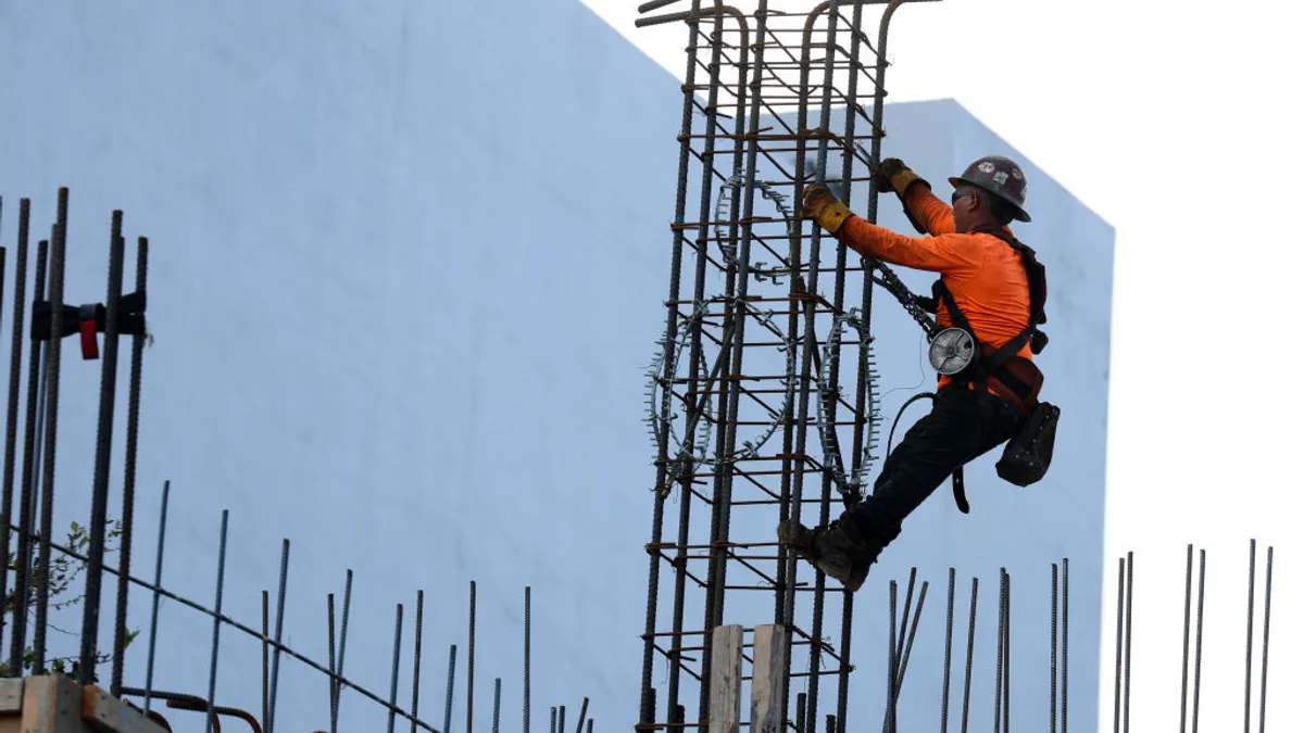 A construction worker in a hard hat uses steel rebar during the building of a condo tower.