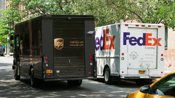 A UPS van passes by a FedEx vehicle on the street.