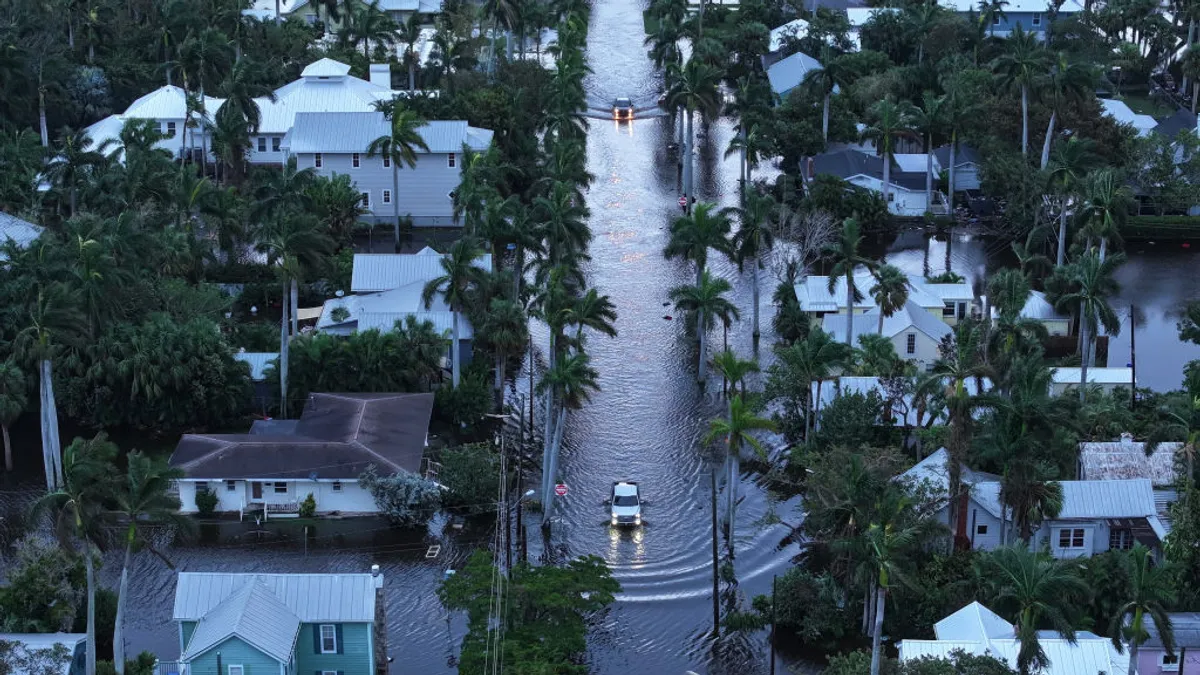 Two vehicles travel down a flooded roadway in Punta Gorda, Florida.