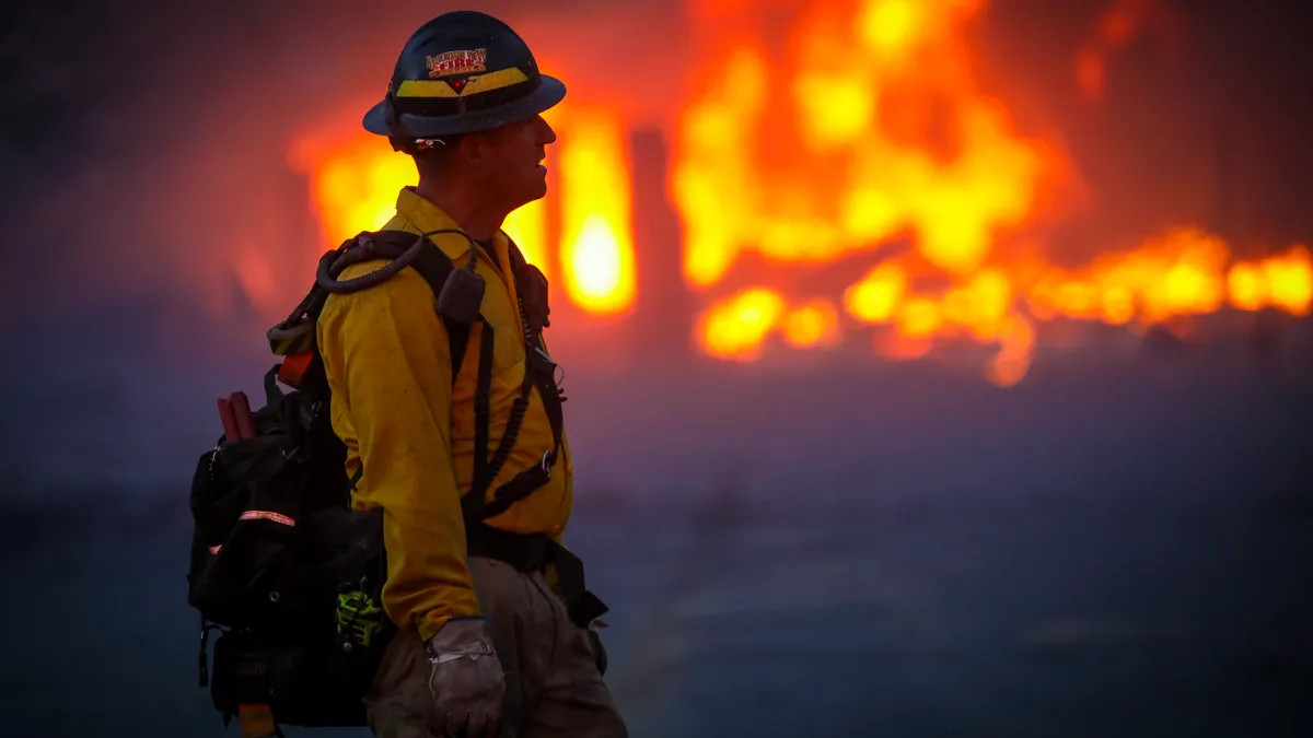 Partial silhouette of a fireman, with a Colorado wildfire burning behind him.