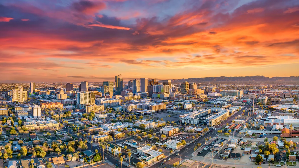 A city skyline beneath a cloudy, orange sky.