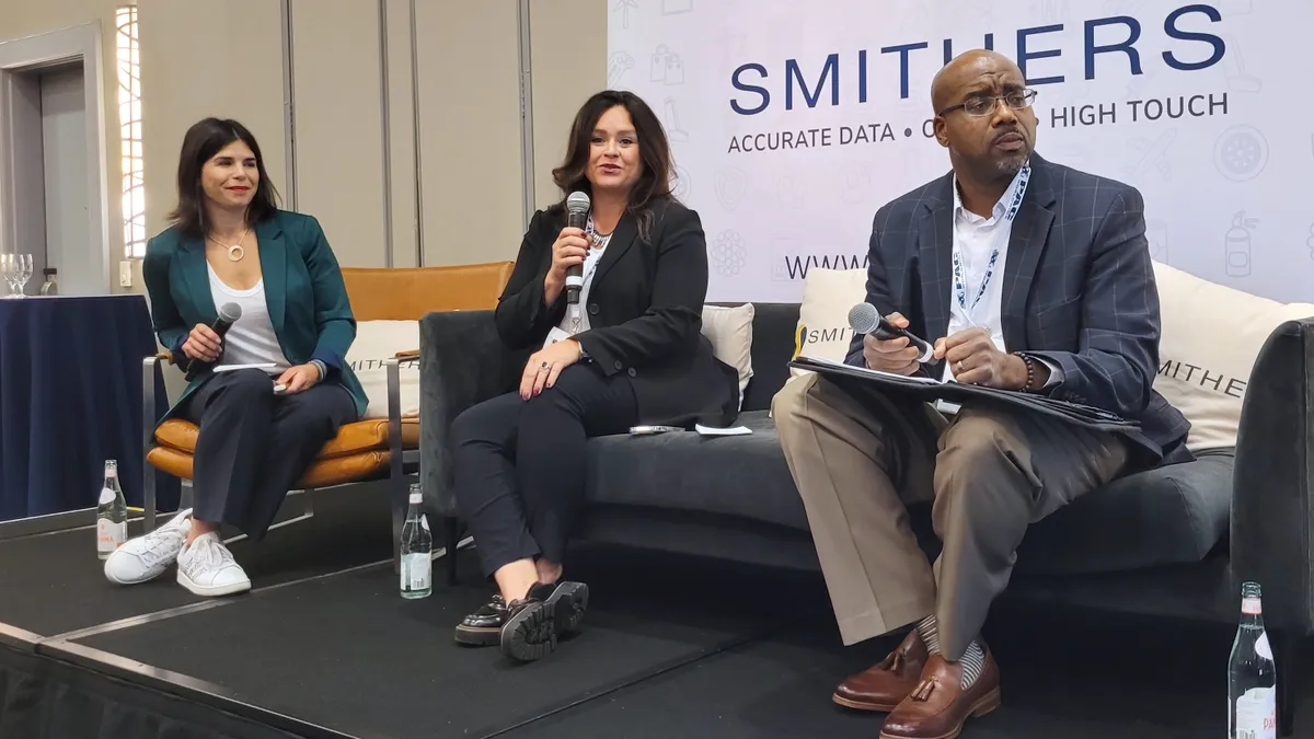 Three people sitting on a stage during a panel discussion at a conference.