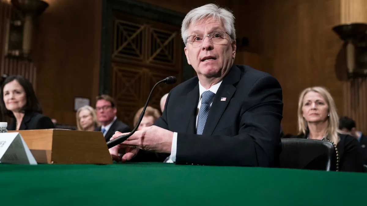 Federal Reserve Board Governor Christopher Waller sits at table speaking.