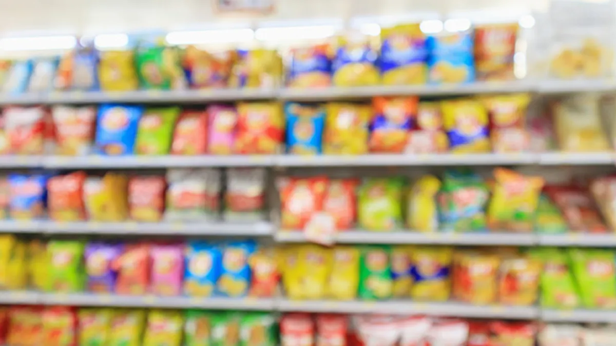 Blurred view of chip packages arranged on store shelves, creating a colorful display.