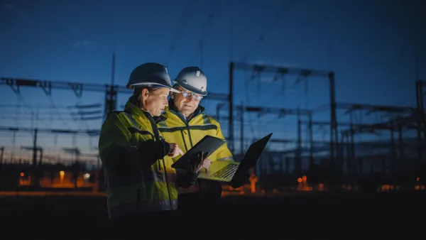 electrical engineers discussing over digital tablet at dark power station