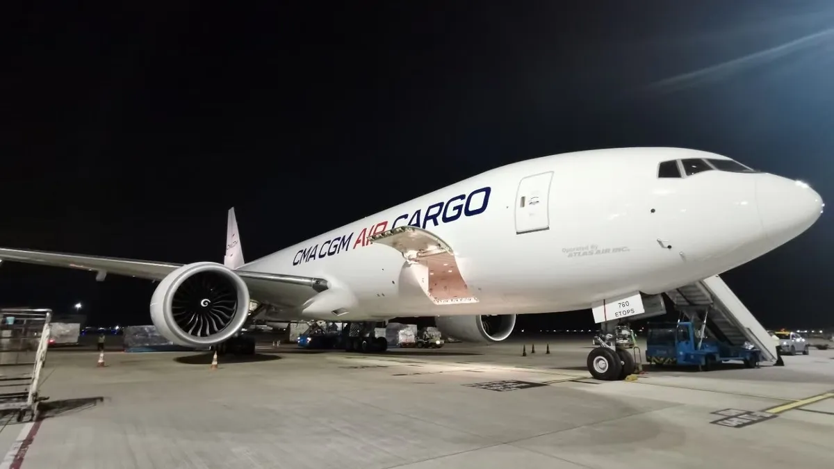 A CMA CGM Air Cargo-branded B777-200F aircraft parked on a runway.