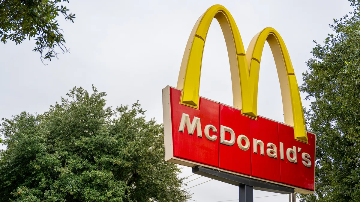 A McDonald's restaurant sign between trees. The sign reads, "McDonald's"