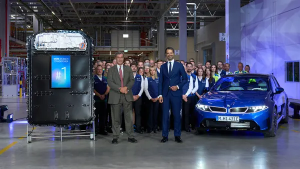 Two executives pose with workers at BMW's new Plant Irlbach-Straßkirchen battery factory in Bavaria to commemorate the start of cell production.
