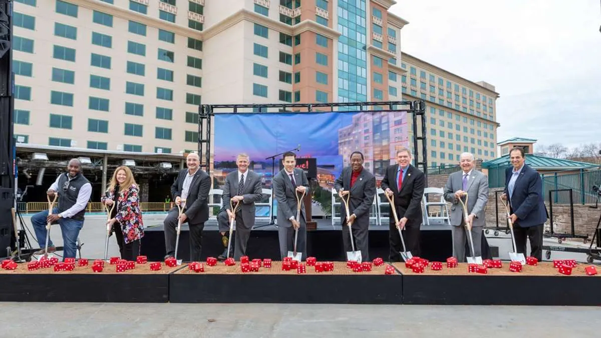 People in suits hold shovels as they pose for a photo.