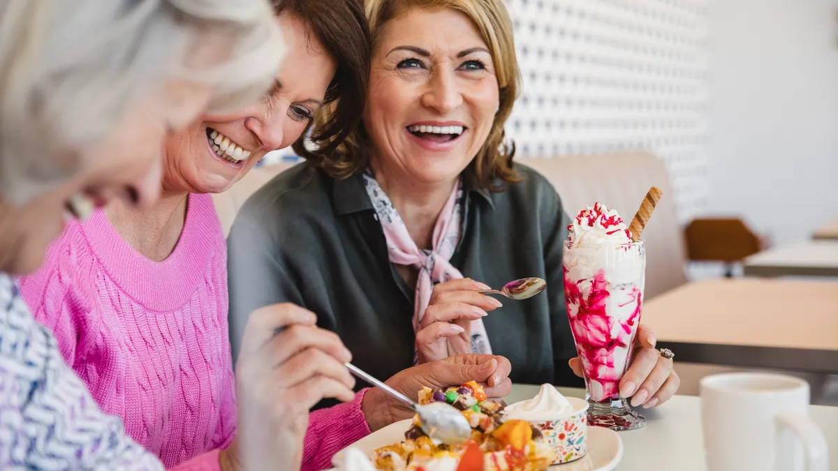 Happy female friends on holiday together eating ice cream sundaes