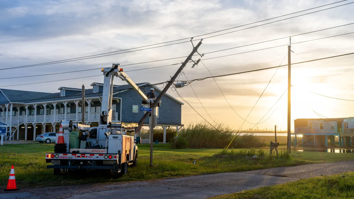 A utility worker works to restore a damaged power-line.