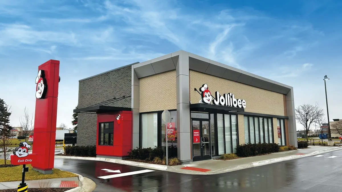 A gray and beige fast food building with red and white brand markings for the chain Jollibee