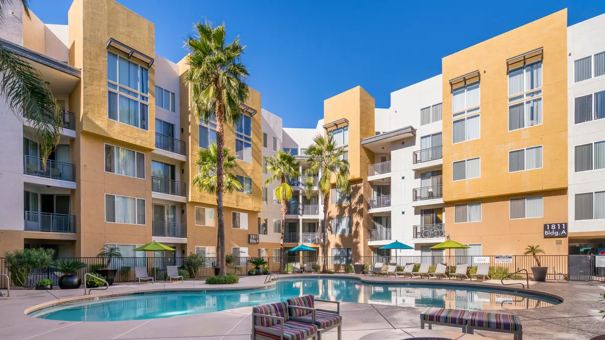 Yellow apartment building with trees and pool inthe foreground