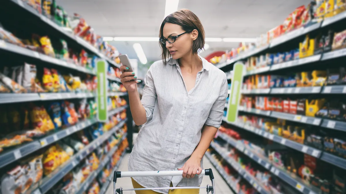 A woman looks at her phone while shopping