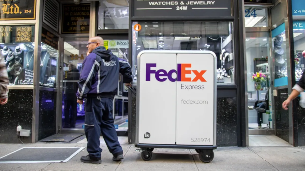 A FedEx Express courier handles an electric cart.