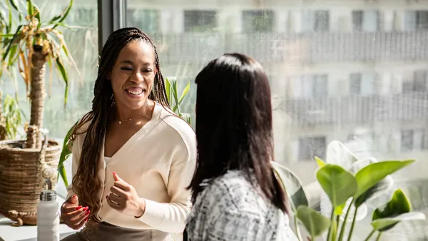 Women chatting during a break by an office window.