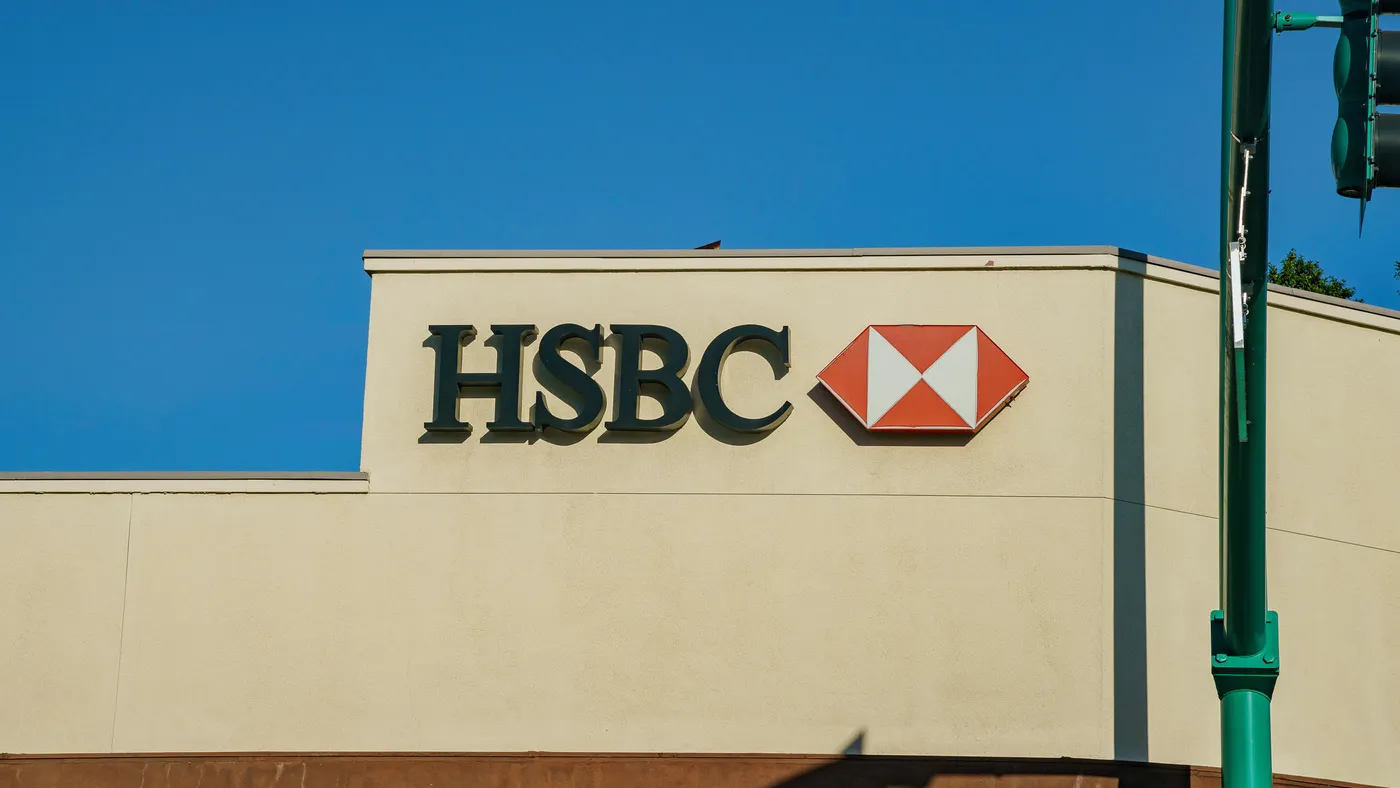 A red and white HSBC logo is prominently displayed on a warm, neutral stucco wall. 