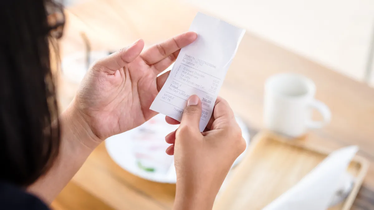 A stock image of a consumer examining a receipt.