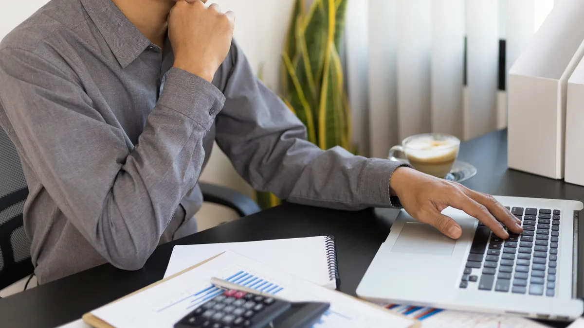 Businessman thinking while working on laptop on desk in office.