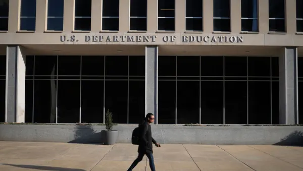 A person walks in front of the exterior of the headquarters for the U.S. Department of Education.