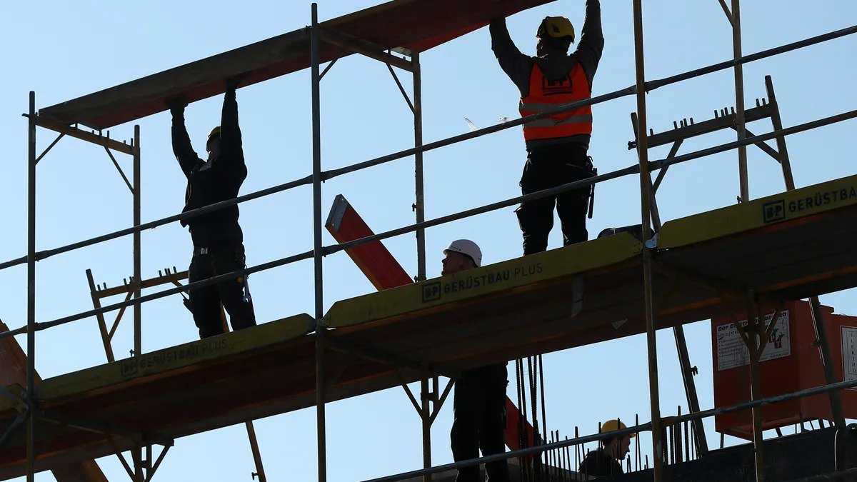 Workers set up scaffolding at the construction site of a new apartment building.