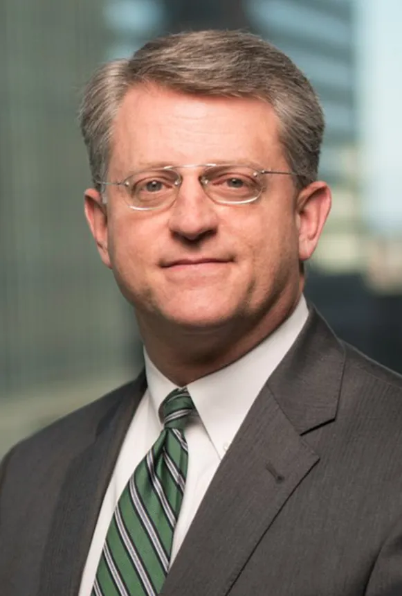 Headshot of a man wearing a grey suit.