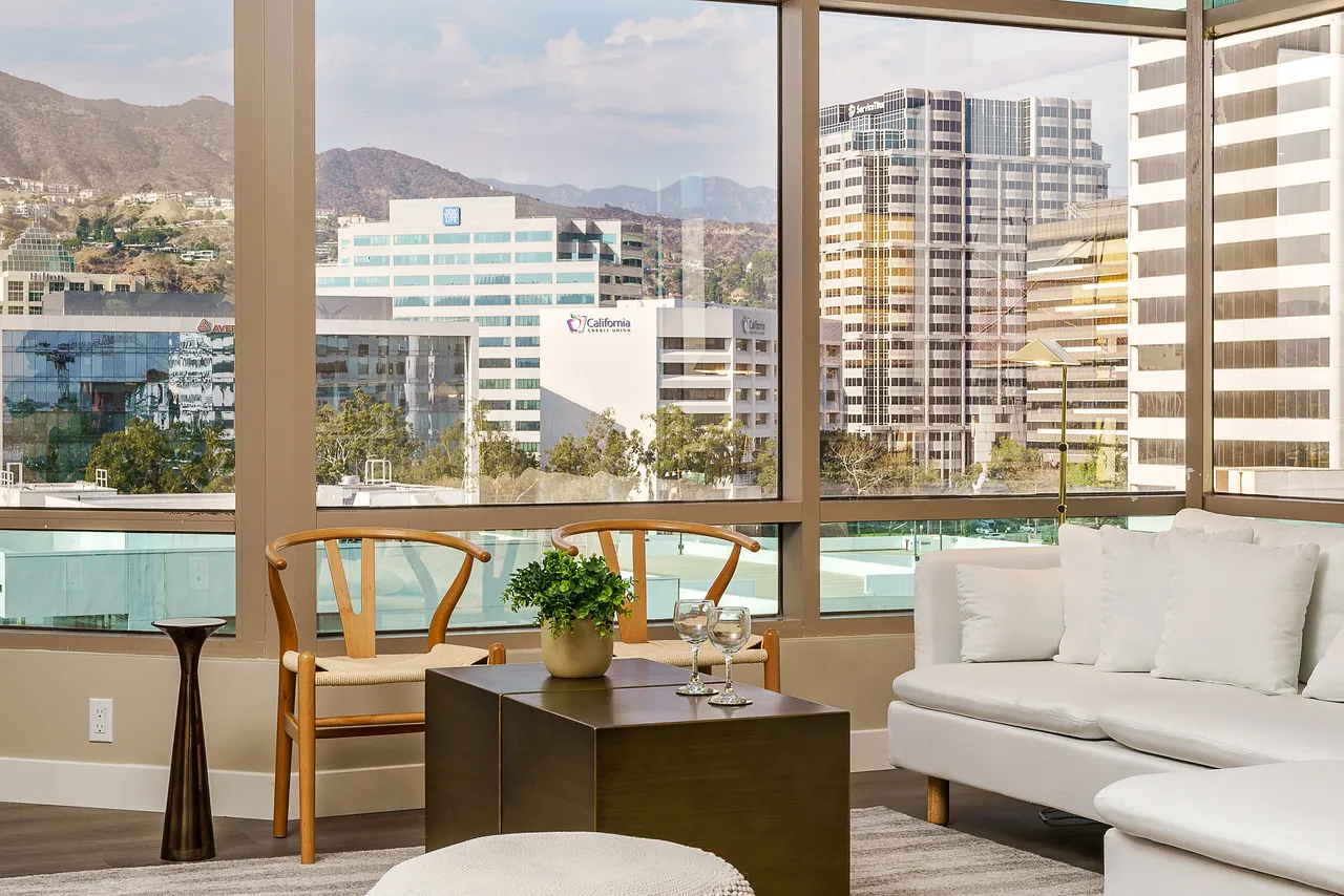 A living room area with windows overlooking a cityscape.