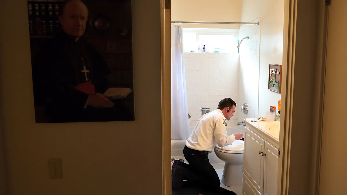 A plumber fixes a toilet.