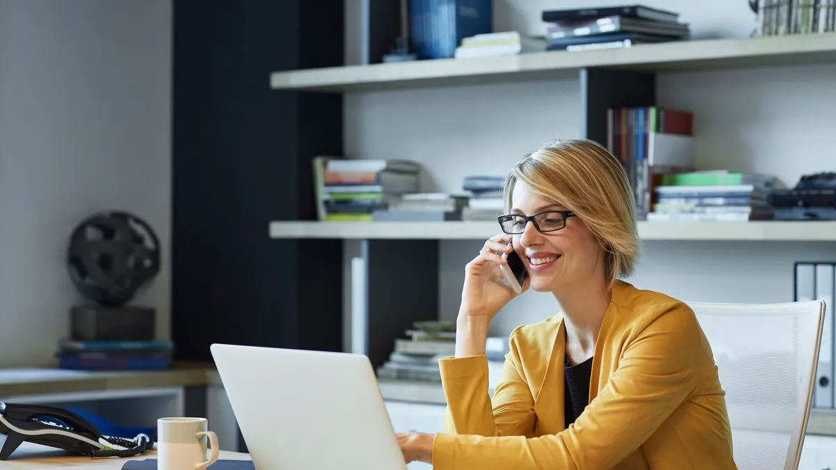 Businesswoman using laptop and smart phone at desk